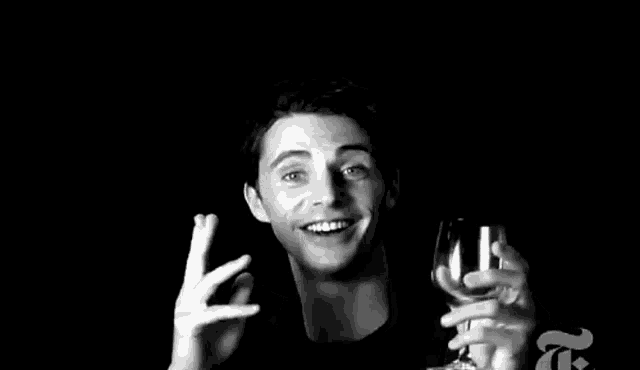 a man in a black shirt is holding a glass of wine in his hand .
