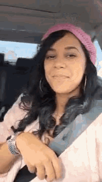 a woman in a pink hat is sitting in a car .