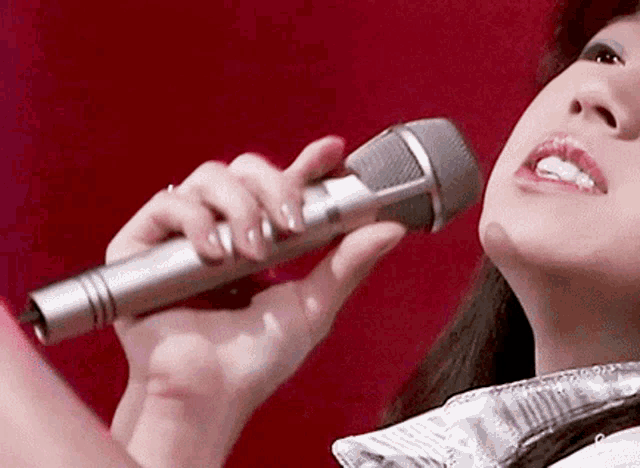 a woman is singing into a silver microphone