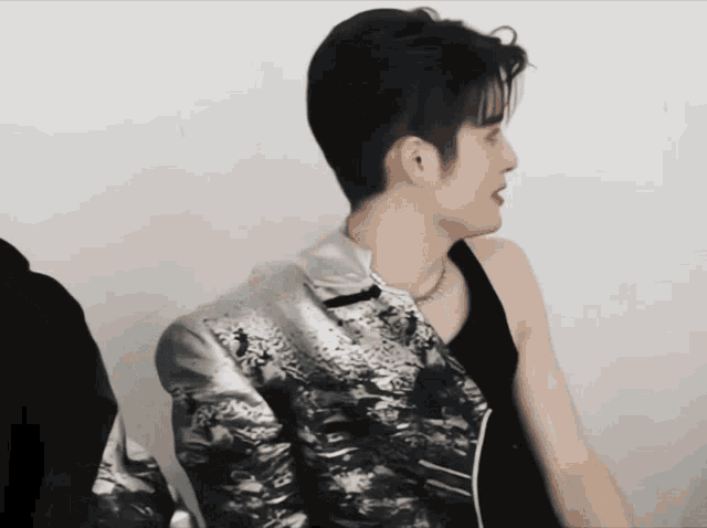a man in a black tank top and silver jacket