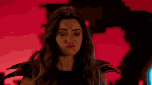 a woman is making a funny face with her eyes closed in a dark room .