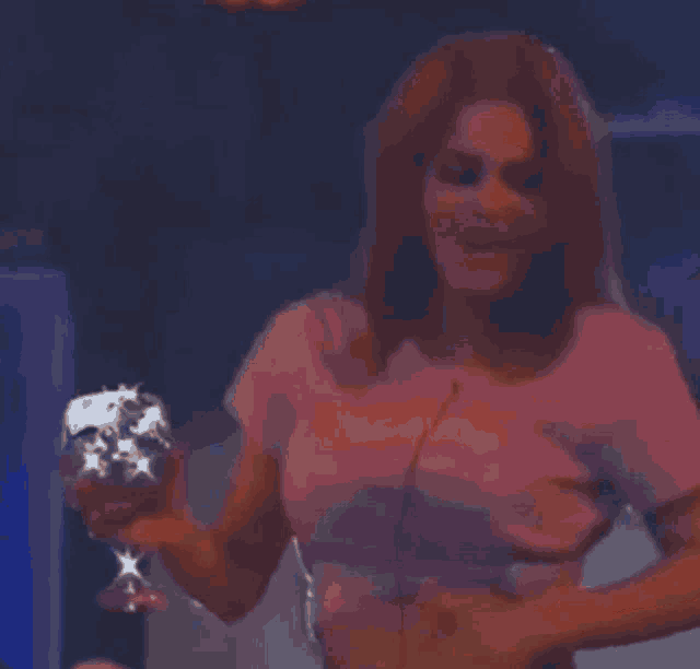 a woman is dancing in a red room while holding a blue bottle .