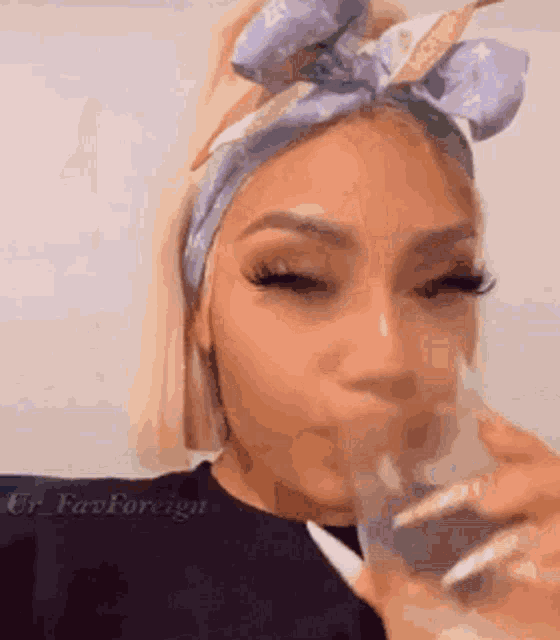 a woman wearing a bandana and a headband is drinking from a glass .