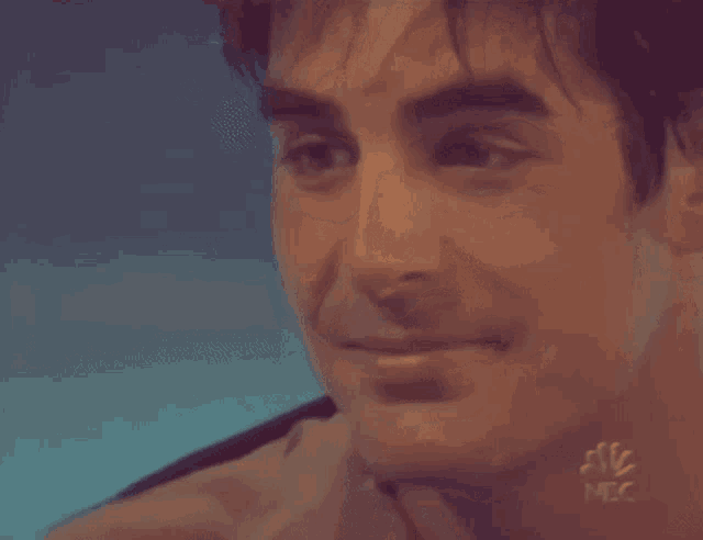 a close up of a man 's face with the letters nbc on his neck