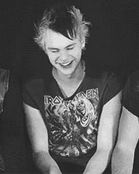 a black and white photo of a man wearing an iron maiden t-shirt .