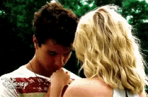 a man is kissing a woman 's hand while wearing a disney shirt