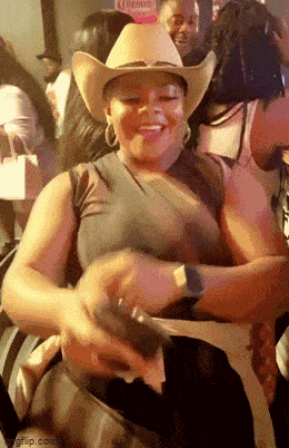 a woman wearing a cowboy hat is dancing in a crowd of people .