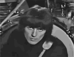 a black and white photo of a man in front of a drum set .