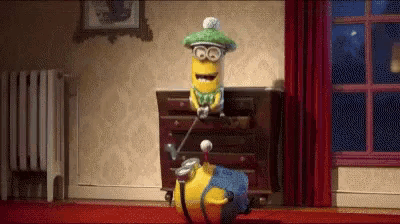 a cartoon minion is playing golf in a room while wearing a green hat and holding a golf club .