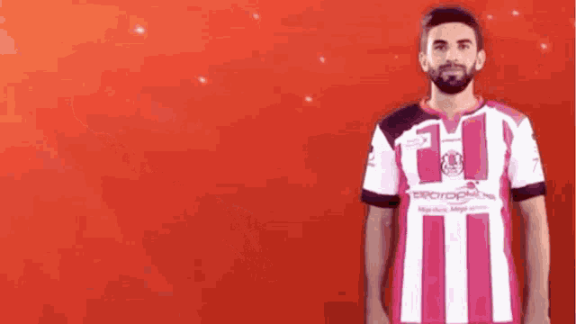 a man with a beard wearing a pink and white striped soccer jersey .