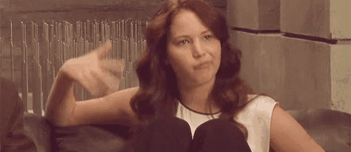 a woman is sitting on a couch making a funny face while making a funny face .