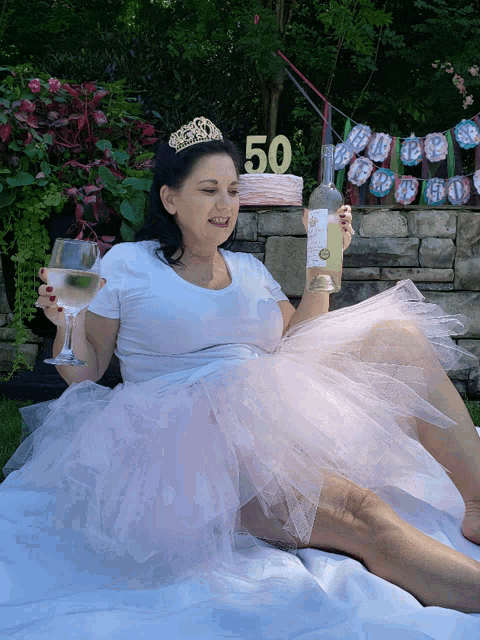 a woman wearing a tiara holds a bottle of wine and a glass of wine