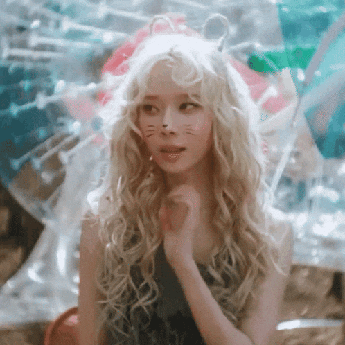 a woman with blonde curly hair and a cat face painted on her face