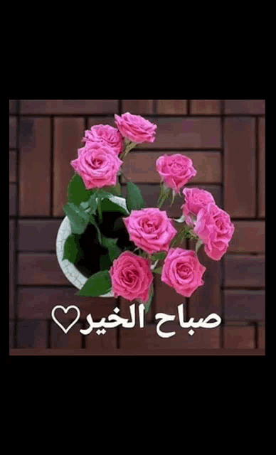 a bunch of pink roses in a white pot with arabic writing