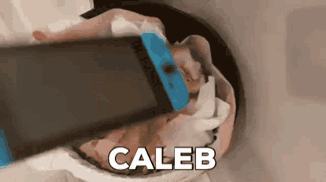 a person is holding a nintendo switch in a trash can with the name caleb written on it .