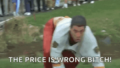 a man is kneeling down in the grass with the words `` the price is wrong bitch '' written next to him .