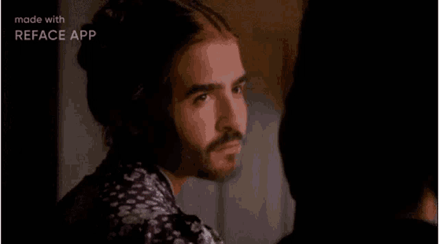a man with long hair and a beard is standing next to a woman in a room .