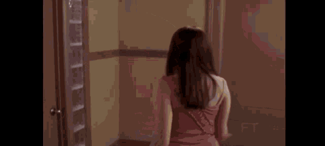 a woman in a pink dress is standing in front of a glass door .