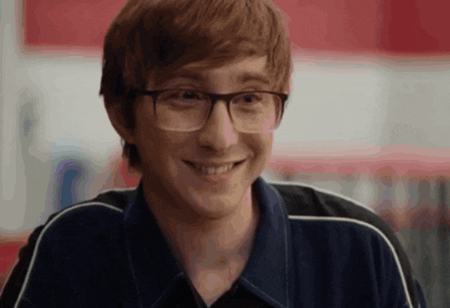 a young man wearing glasses and a black shirt smiles for the camera