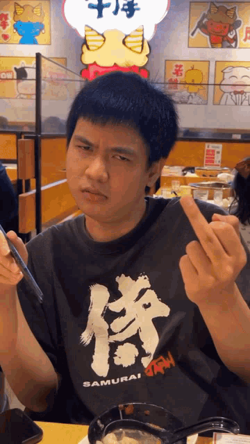 a man wearing a black shirt that says samurai giving the middle finger