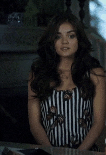 a woman wearing a black and white striped top looks at the camera