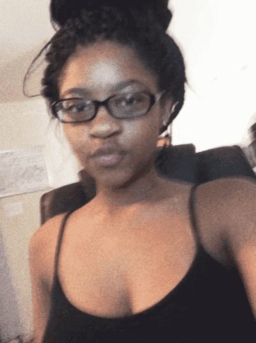 a woman wearing glasses and a black tank top taking a selfie