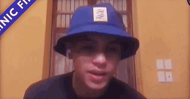 a young man wearing a blue hat and sunglasses is sitting in a room .