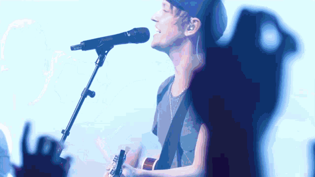 a man is singing into a microphone while playing a guitar