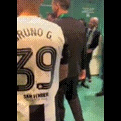 a man in a suit is standing next to a man wearing a jersey with the number 39 on it