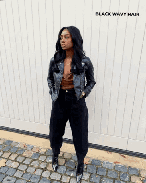 a woman with black wavy hair is standing on a cobblestone street