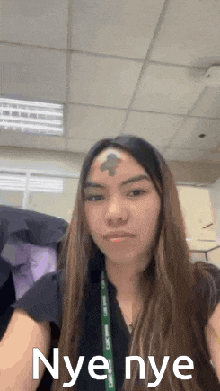 a woman with a cross on her forehead is taking a picture of herself .