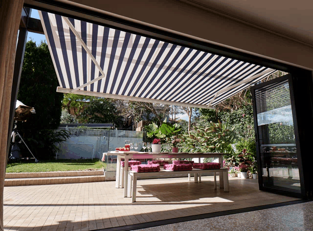 a blue and white striped awning over a patio table and benches