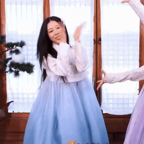 a woman in a blue dress is waving her hand