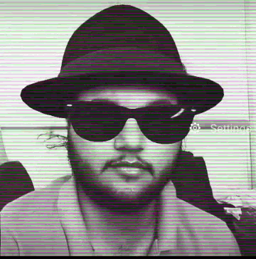 a man wearing a hat and sunglasses is standing in front of a striped background .