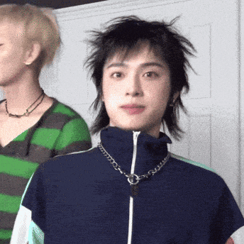 a woman wearing a green and black striped shirt is standing next to a man wearing a blue jacket