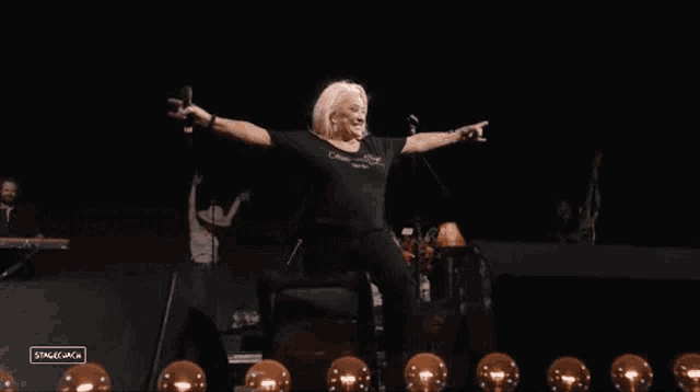 a woman is singing into a microphone on stage while wearing a black t-shirt that says stagecoach
