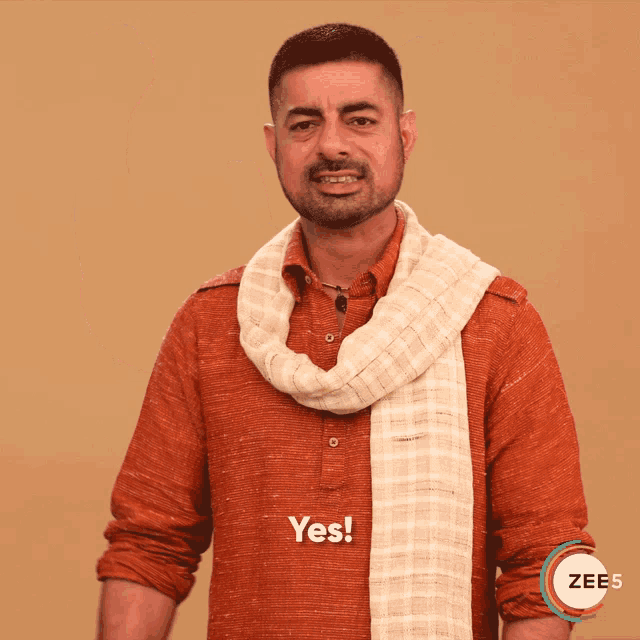 a man wearing an orange shirt and a white scarf says " yes "