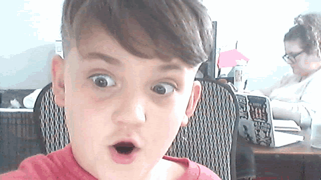 a young boy with a surprised look on his face is sitting in a chair