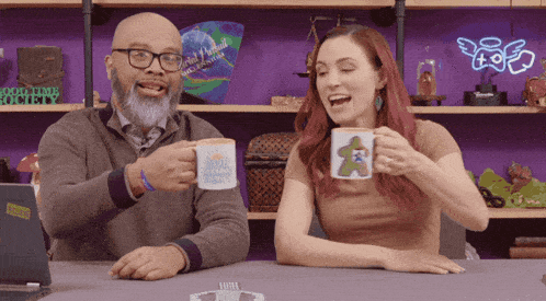 a man and a woman are sitting at a table drinking coffee from mugs that say world hunger project