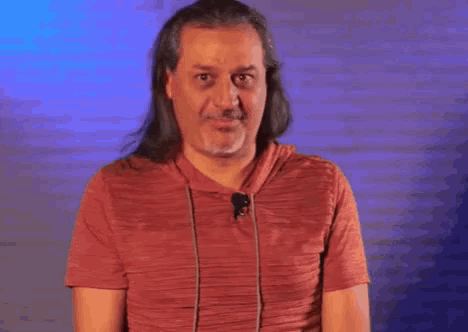 a man with long hair is giving a thumbs up