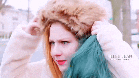 a woman with blue hair is wearing a fur hood