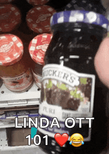 a person is holding a jar of blueberry jam with the words linda ott 101 written on the bottom