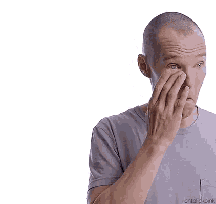 a man with a shaved head is touching his forehead with his hand