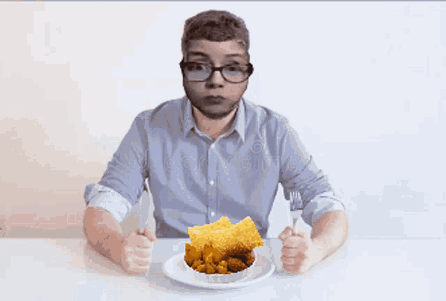 a man with glasses is sitting at a table eating a plate of food