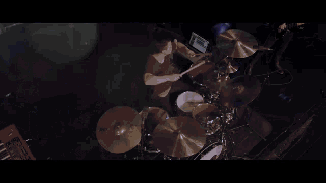 a man is playing drums in a dark room with a cymbal that says sabian on it