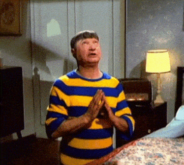 a man wearing a blue and yellow striped shirt is praying in a bedroom