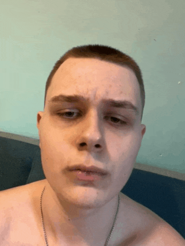 a shirtless man with a necklace around his neck is looking at the camera