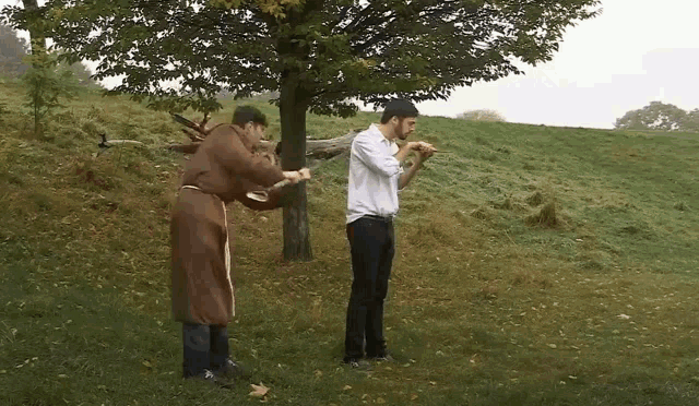 two men standing next to each other in a grassy field