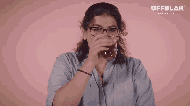 a woman with glasses is holding a glass of tea in front of a pink background that says offblok