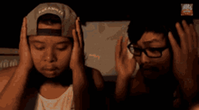 a man and a woman covering their ears with their hands .